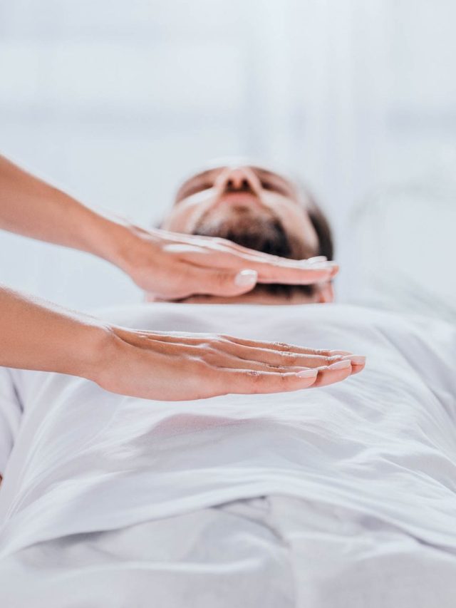 cropped shot of bearded man receiving reiki healing session above stomach